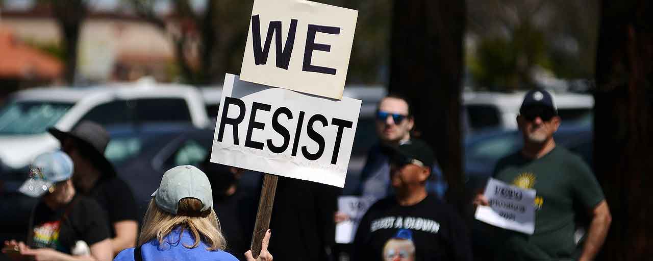 Protesters with signs saying We Resist